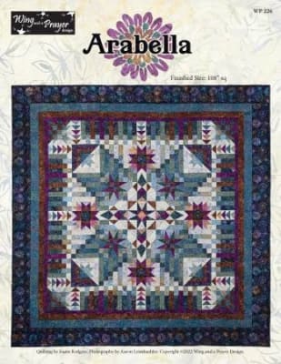 Arabella BOM pattern by Wing and A Prayer shows a large center medallion quilt with star blocks, and a variety of other quilt blocks in shades of ruby and aquamarine.