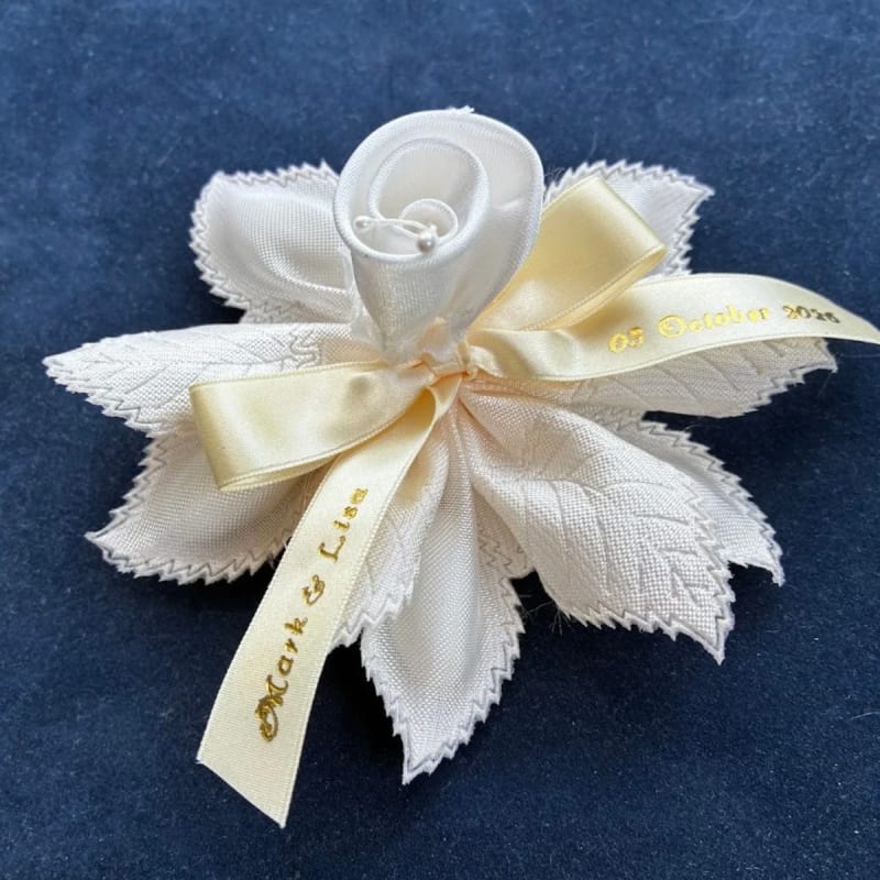 Ribbon flower with leafy petals holds five sugared almonds.