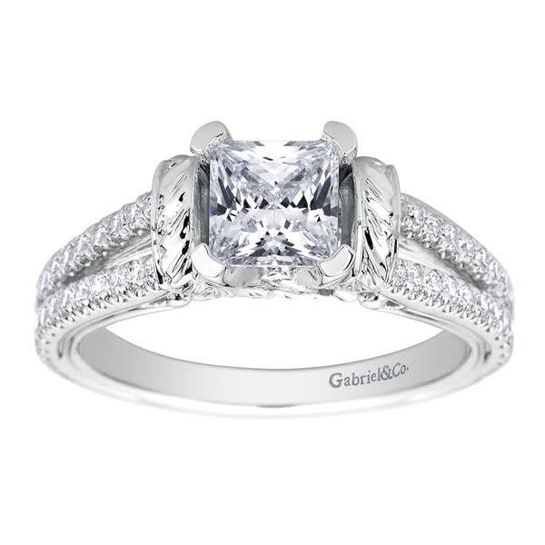 This diamond studded split shank princess cut diamond engagement ring glistens with 0.39 carats of round brilliant diamonds, all cushioning a princess cut center diamond.