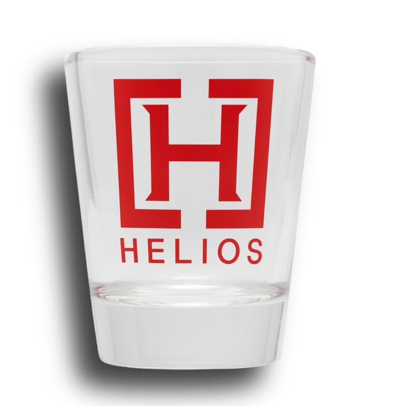 Helios Reserve Shot Glass â€“ clear glass with bold branding, perfect for tattoo studio decor or drinking