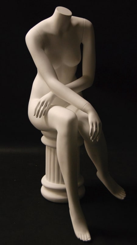 Headless female mannequin in a seated pose with a matte white finish on a matching pedestal stool.