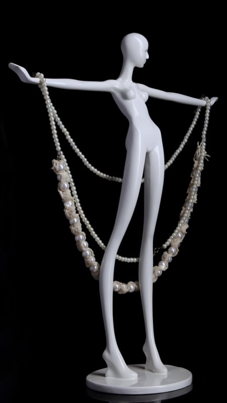 Miniature gloss white fiberglass mannequin head for jewelry display featuring an integrated base for showcasing earrings and necklaces.