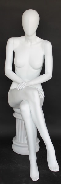 Female egghead mannequin in seated pose. Her legs are crossed with her hands on her lap.