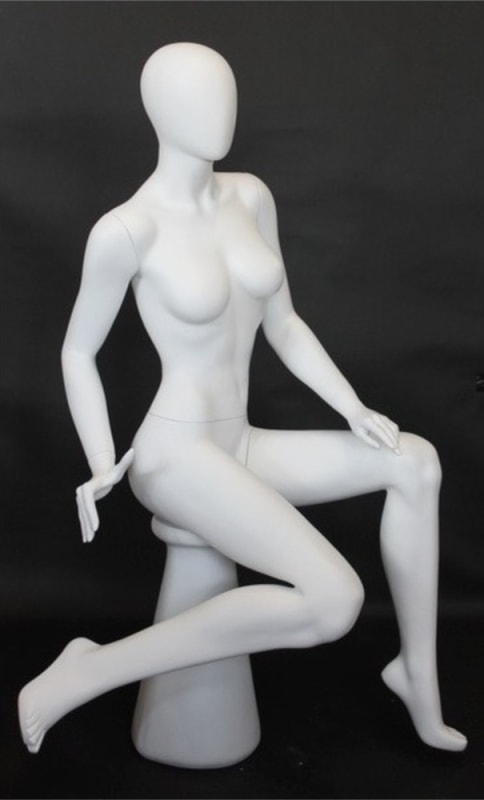 Female egghead mannequin in seated pose. Her legs are crossed with her hands on her lap.