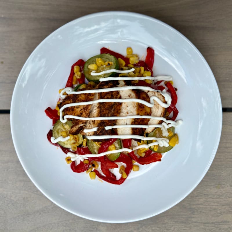 A zesty and satisfying bowl of chili-lime grilled chicken mixed with roasted corn, red bell peppers, zucchini, and fluffy basmati rice, all tossed in a creamy lime crema sauce for a vibrant Â&nbsp;favorite.