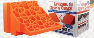 The Tri-Lynx Lynx Stop 'N Chock (2-Pack), model 00018-2PK, is a pair of orange plastic wheel chocks for RVs, trailers, and campers. The chocks are designed to be used with Lynx Levelers for a complete leveling and stabilization system.