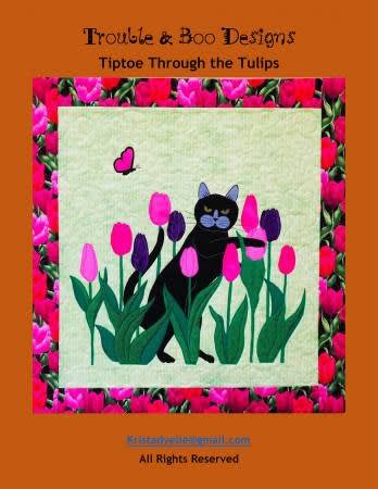 TIPTOE THROUGH THE TULIPSby Trouble & Boo shows a  black cat and pink tulips.