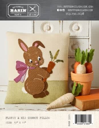 Flopsy & His Carrot Pillow  PATTERN  from Buttermilk Basin shows a pillow with a h brown bunnies and orange carrot.