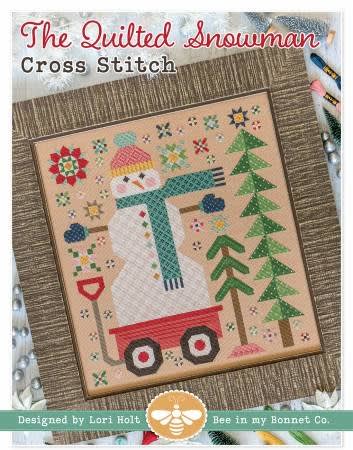 The Quilted Snowman CROSS STITCH Pattern  from It's Sew Emma shows a large snowman riding in a red wagon,  with a blue stocking cap, blue mittons and a blue scarf along with winter pines and scenery.