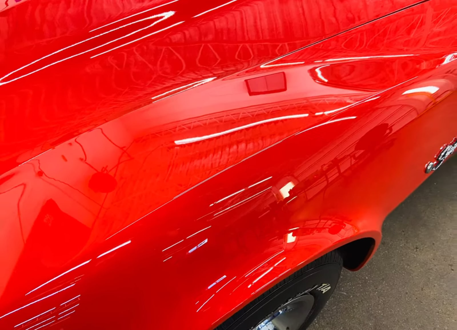 Paint correction close-up on red vehicle showing restored gloss and clarity