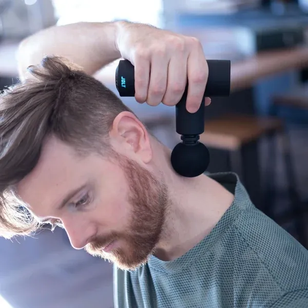 Le pistolet de massage Jolt Mini utilisé sur les cervicales, tenu d'une seule main