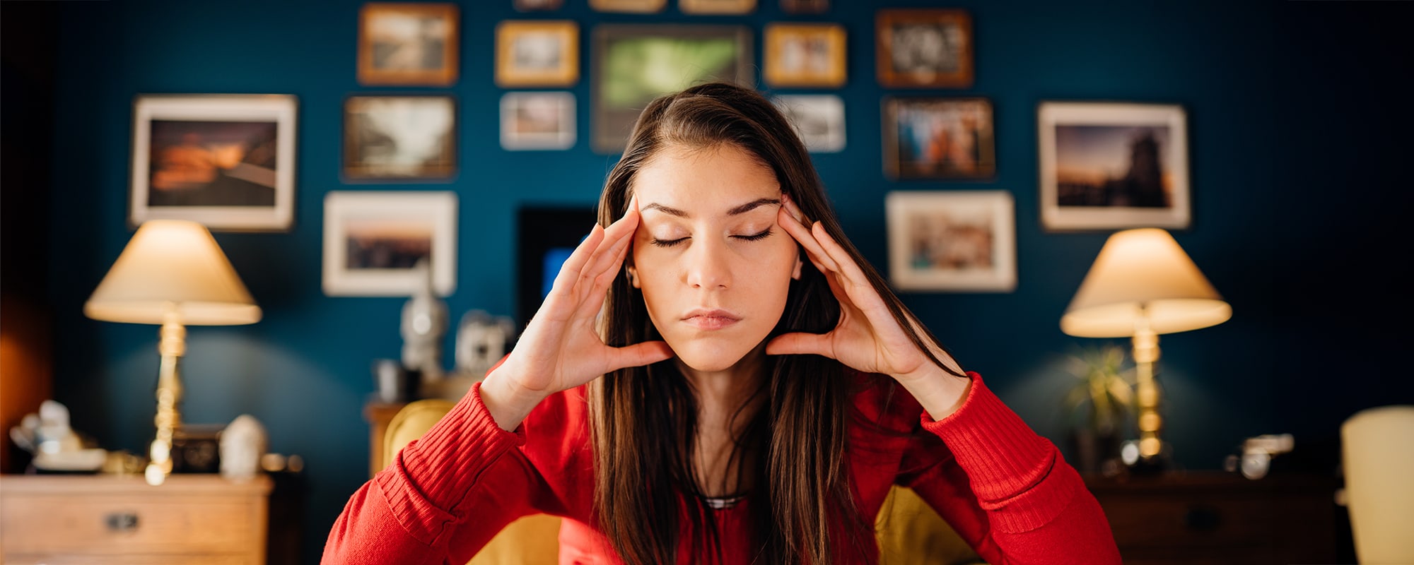 Woman sitting in an office, with hands to temples, overthinking