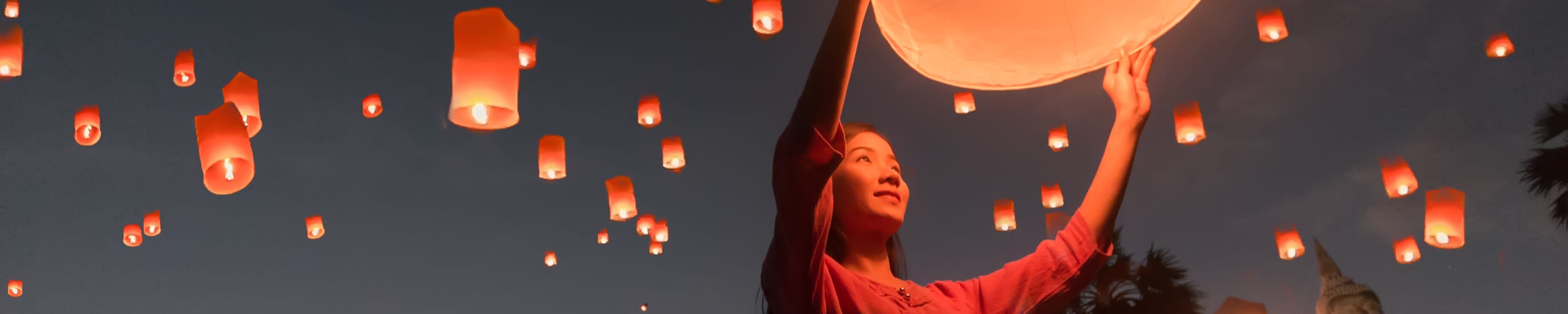 Woman releasing Khom Loi, the sky lanterns during Loi Krathong festival in Chiang Mai, Thailand