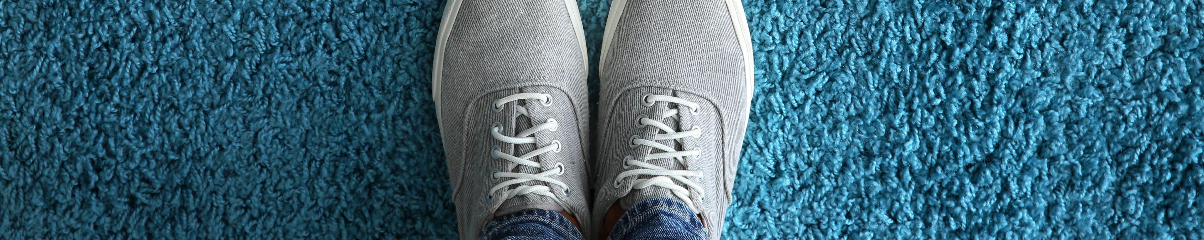 Overhead blue of person's sneakers standing on arrow pointing forward