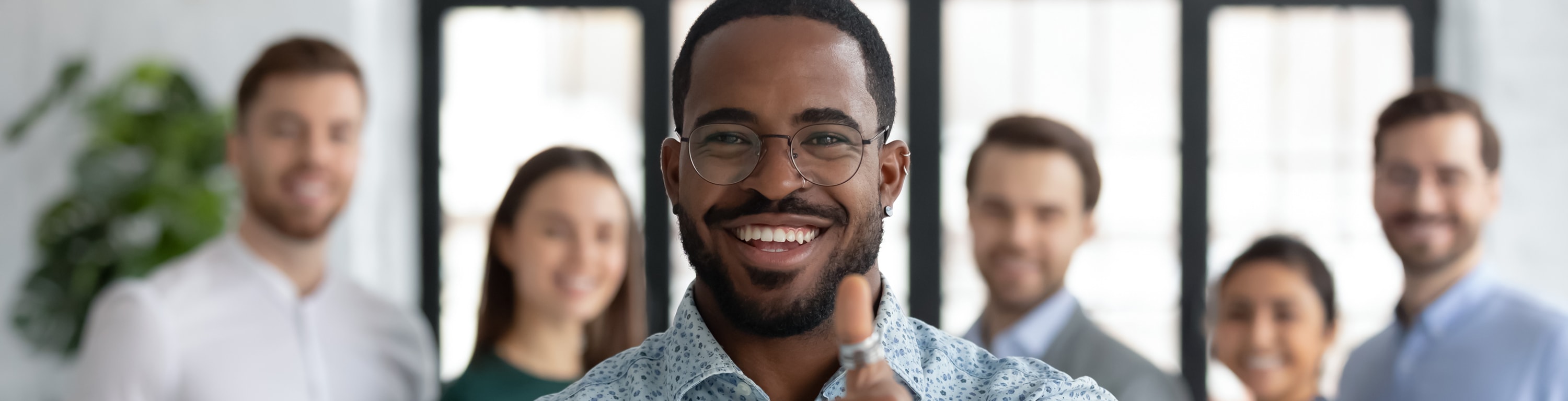 Happy African American male business leader making thumbs up like gesture at camera.