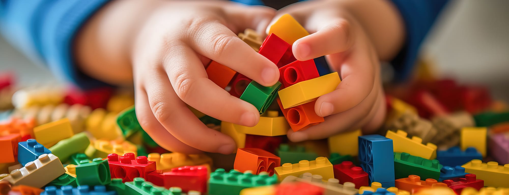 Close-up photograph of a small childs hands playing with a colorful set of building blocks