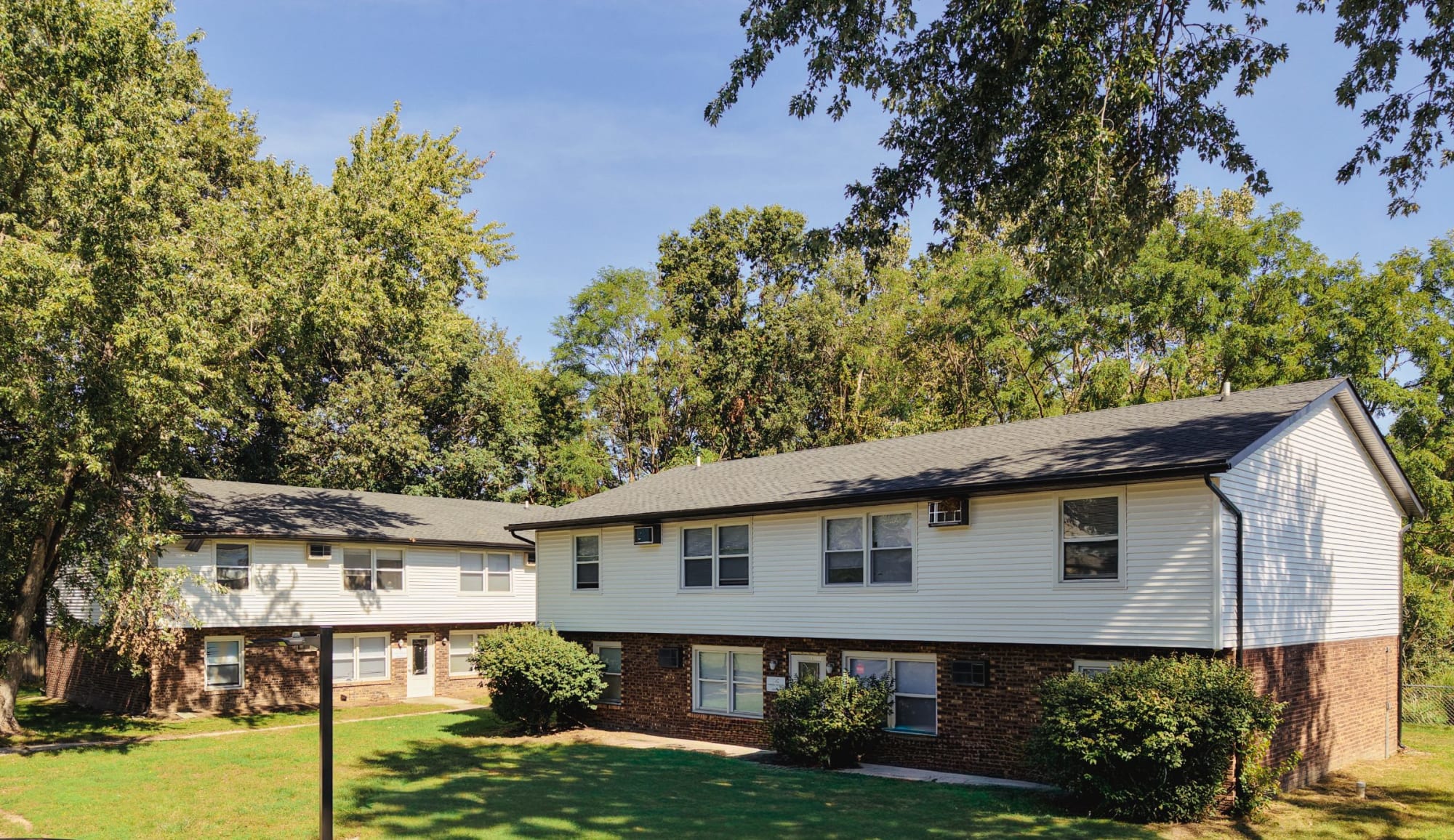 Two-story brick and siding buildings beneath mature trees