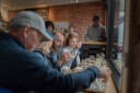 Dunedin Craft Distillers customers enjoying a spirits tasting session at a wooden counter, with small glasses and bottles on display.