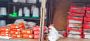 Shelves packed with white and green poultry feeders, waterers, and bags of Sharpes animal feed and chick crumbles, plus large FeedSafe NZ feed bags. Supplies for raising hens.