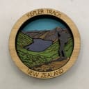Laser-cut and painted wooden craft depicting New Zealand's Kepler Track, with mountains, lake, and a hiker.