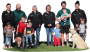 Scott's Seedlings family and team, including children and a dog, on grass. Adults wear branded workwear for their plant business.