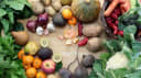 Fresh, colourful array of fruits and vegetables: spinach, potatoes, onions, kiwis, mandarins, apples, pumpkin, and beets on wood.