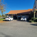 Commercial building with terracotta roof, 'Cellpower' sign, and two white cars parked on asphalt.