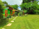Vibrant green and yellow shed in a lush garden with stepping stones and tall trees, representing Hira Oasis, a grower for Nelson Farmers Market.
