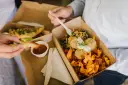 Customers enjoying Herba Gourmet's prepared takeaway meals: falafel with kumara chips & salad, and fish & chips with sauce.
