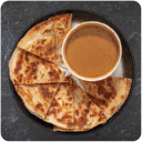 Freshly made, flaky roti flatbread pieces with a rich curry dipping sauce on a dark plate, from Roti Joes prepared food vendor.