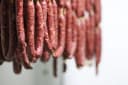 Rows of artisan wild game salami hanging to cure, showcasing the butcher's craft.