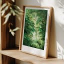 Lush green jungle art print by Studio Peers, framed in light wood and displayed on a wooden shelf.