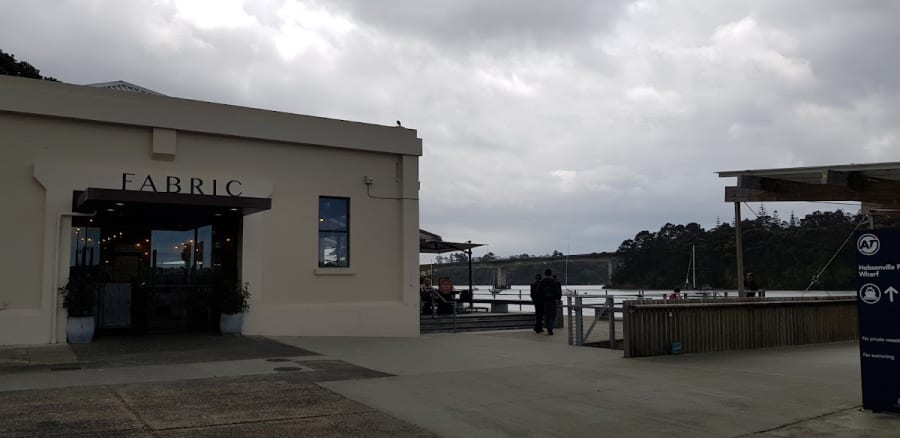 Hobsonville Point Wharf, featuring Fabric cafe, water, and a bridge, the location for Hushwood Candles' craft stall.