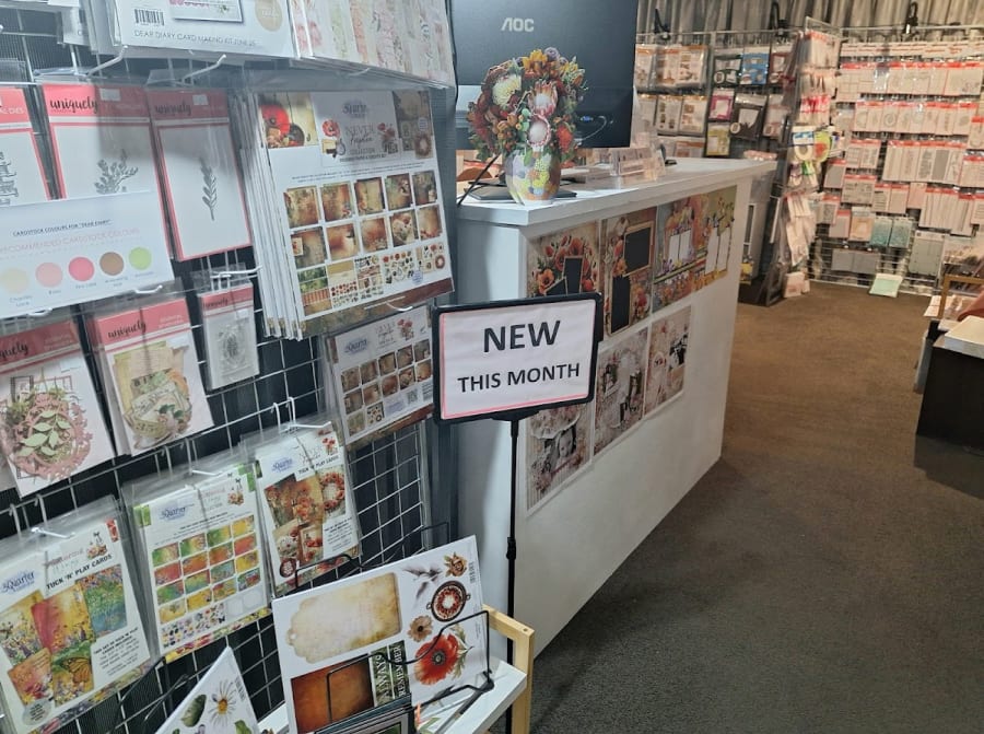 The Crafty Kiwi's extensive display of paper crafting kits, dies, and embellishments, with a 'NEW THIS MONTH' sign.