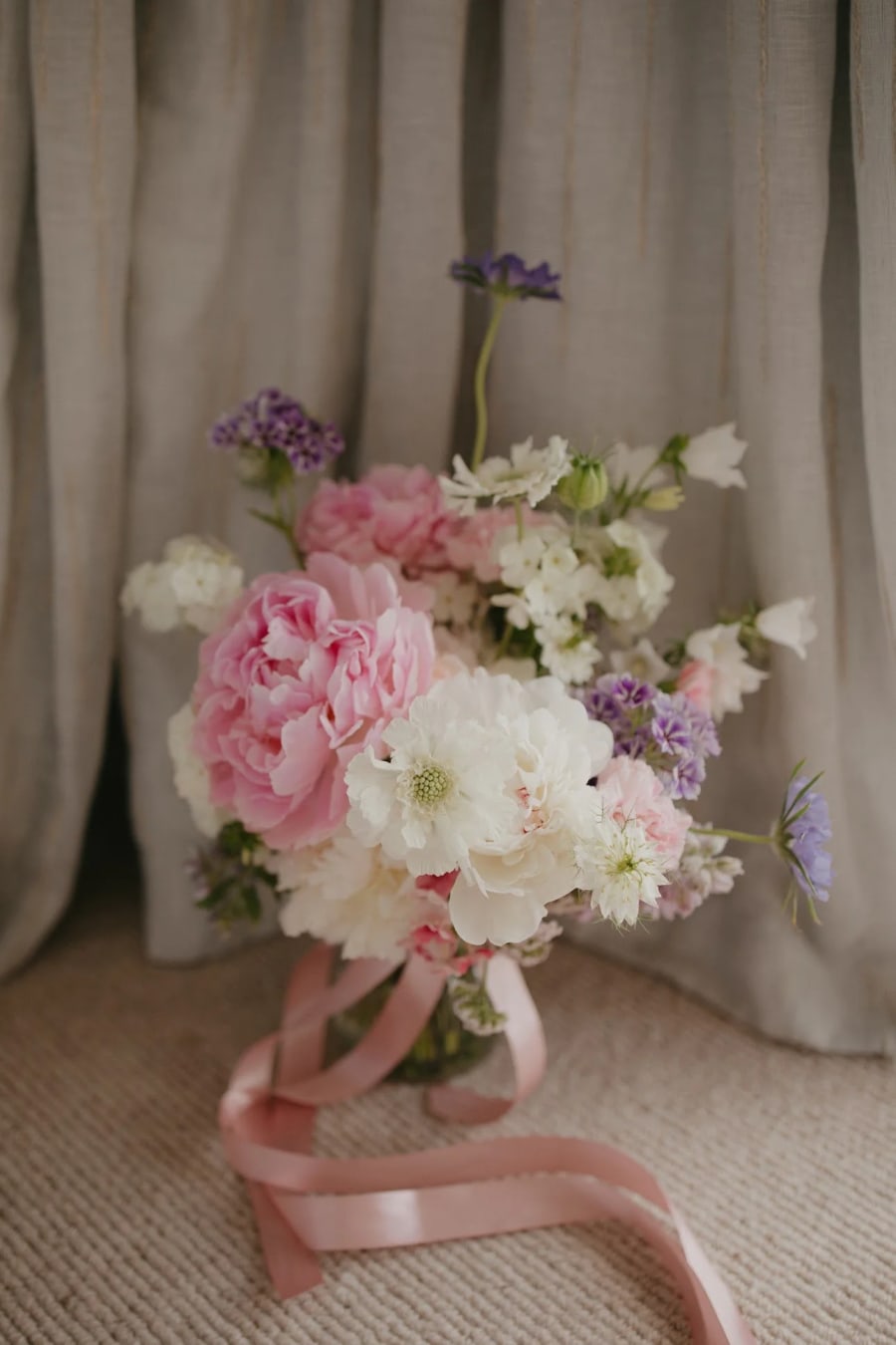 Lush pink and white peony bouquet with purple accents and a flowing pink ribbon, crafted by Florence & Flora, a Napier florist.