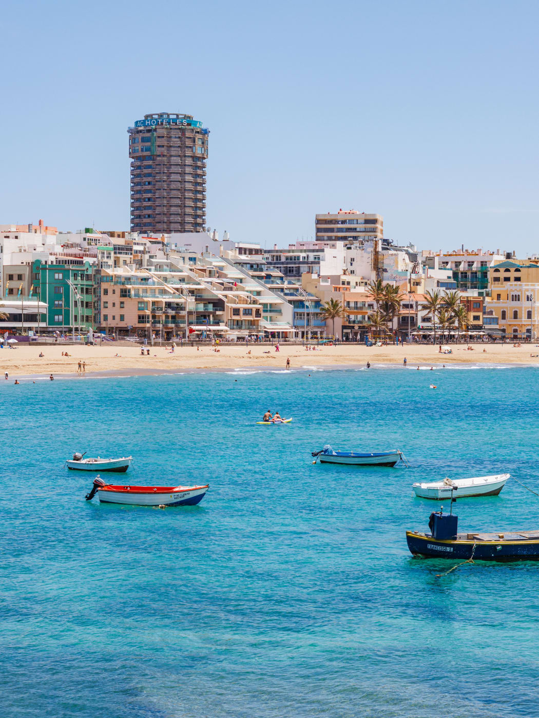 Pequeñas barcas fondeadas frente a la playa de Las Canteras, en Las Palmas, con el paseo marítimo detrás