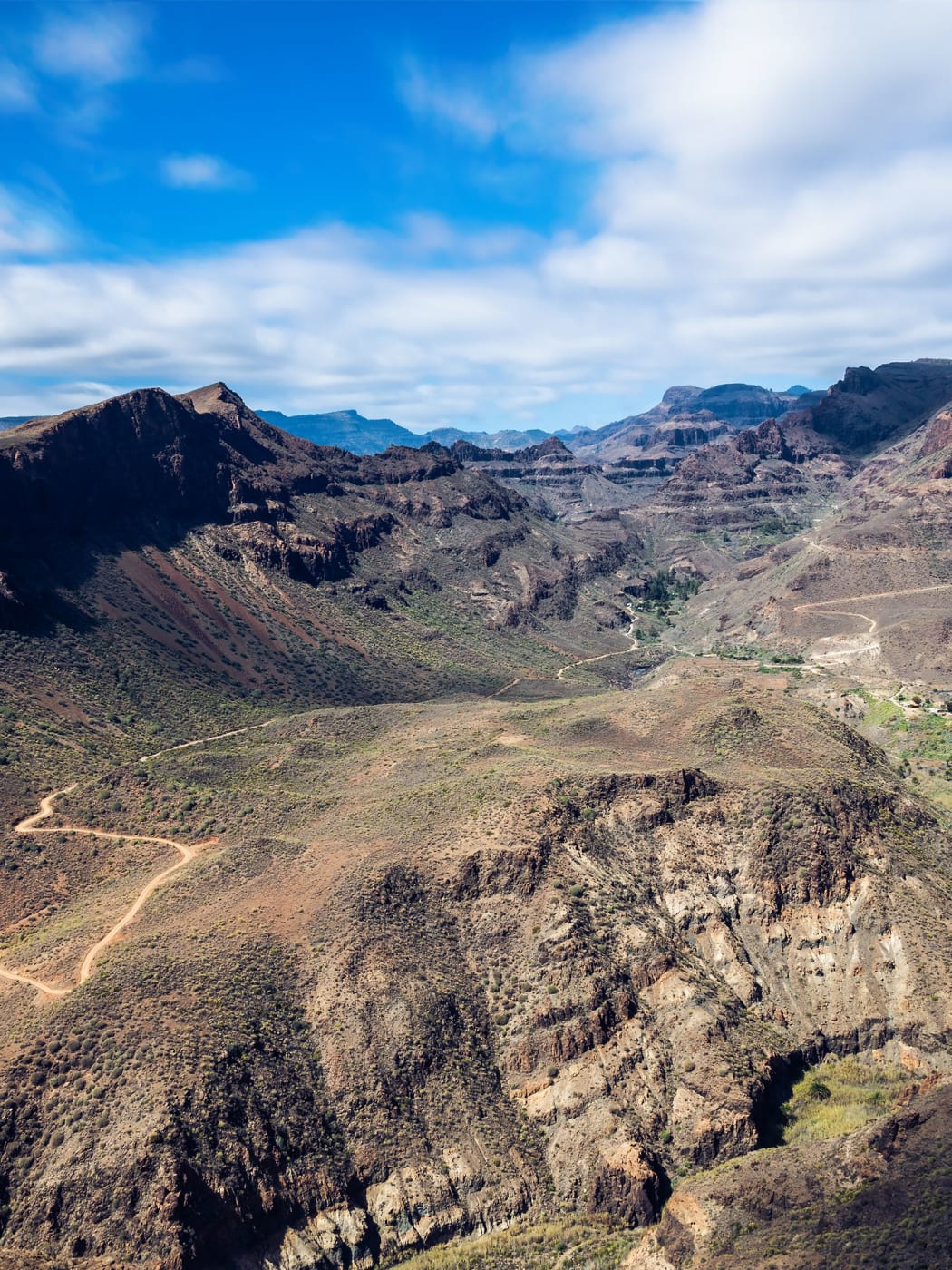 Unpaved tracks winding across the dry mountains of the interior, with ridges and ravines behind