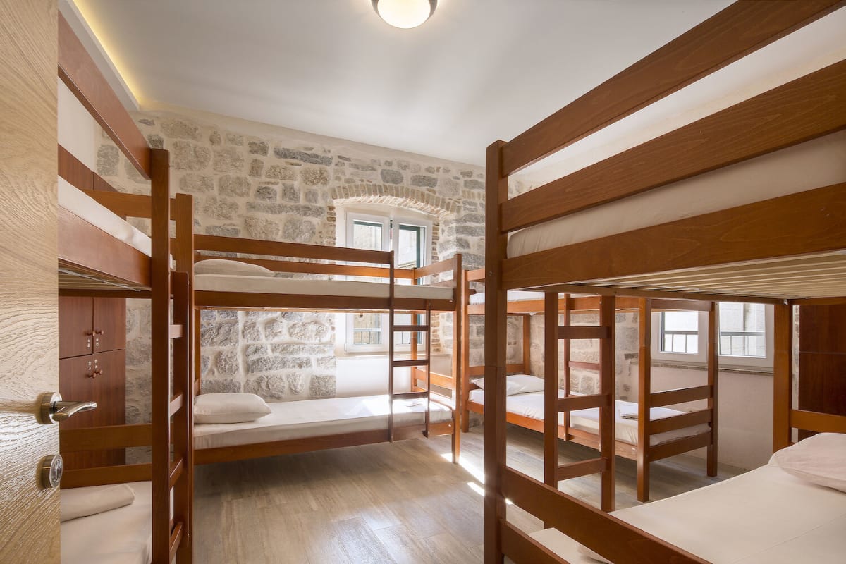 Dormitorio con letti a castello, tavolo e lampade a Hostel Old Town Kotor