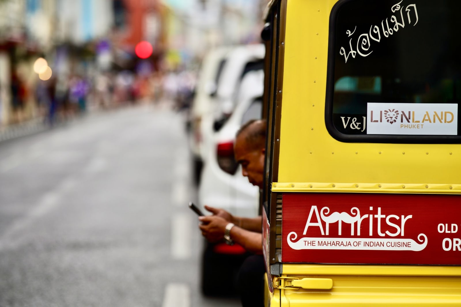 A tuk-tuk waiting in traffic on a Phuket Town street
