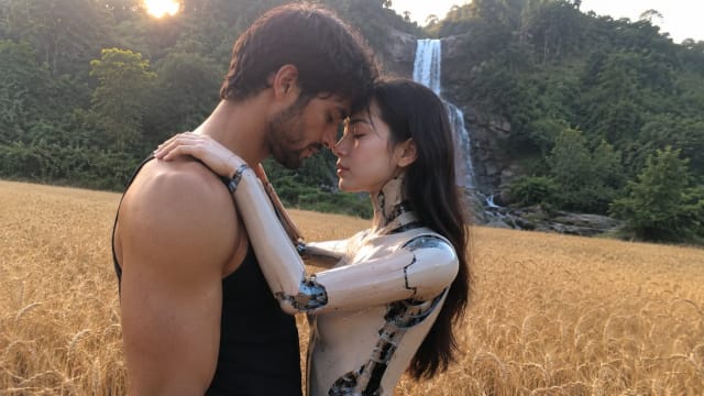 A man embraces a humanoid robot in a wheat field at sunset, capturing the emotional and ethical questions surrounding AI companions and the future of human relationships.