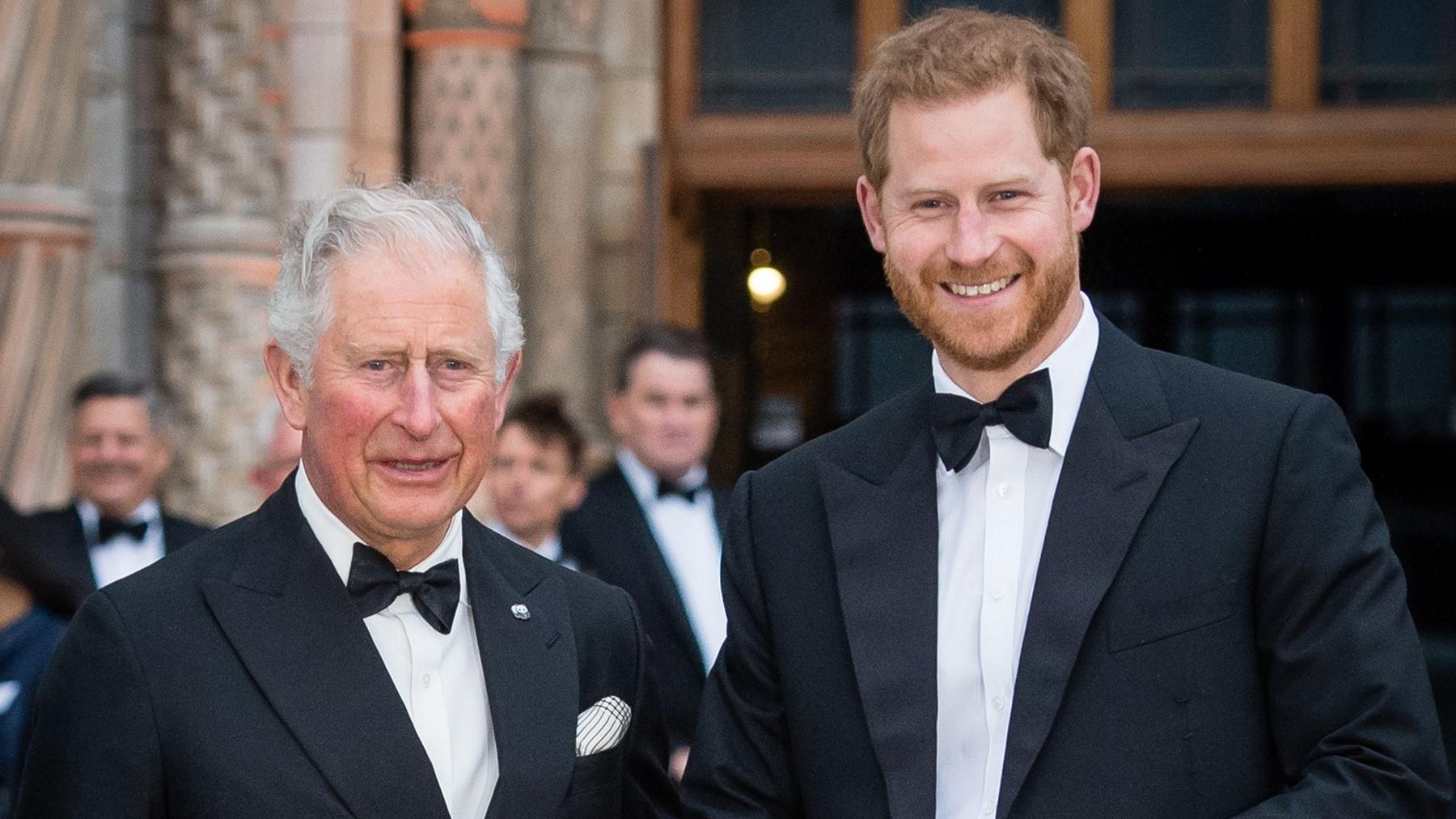 King Charles and Prince Harry both in black tuxedos with bow ties, smiling outdoors at an evening event.