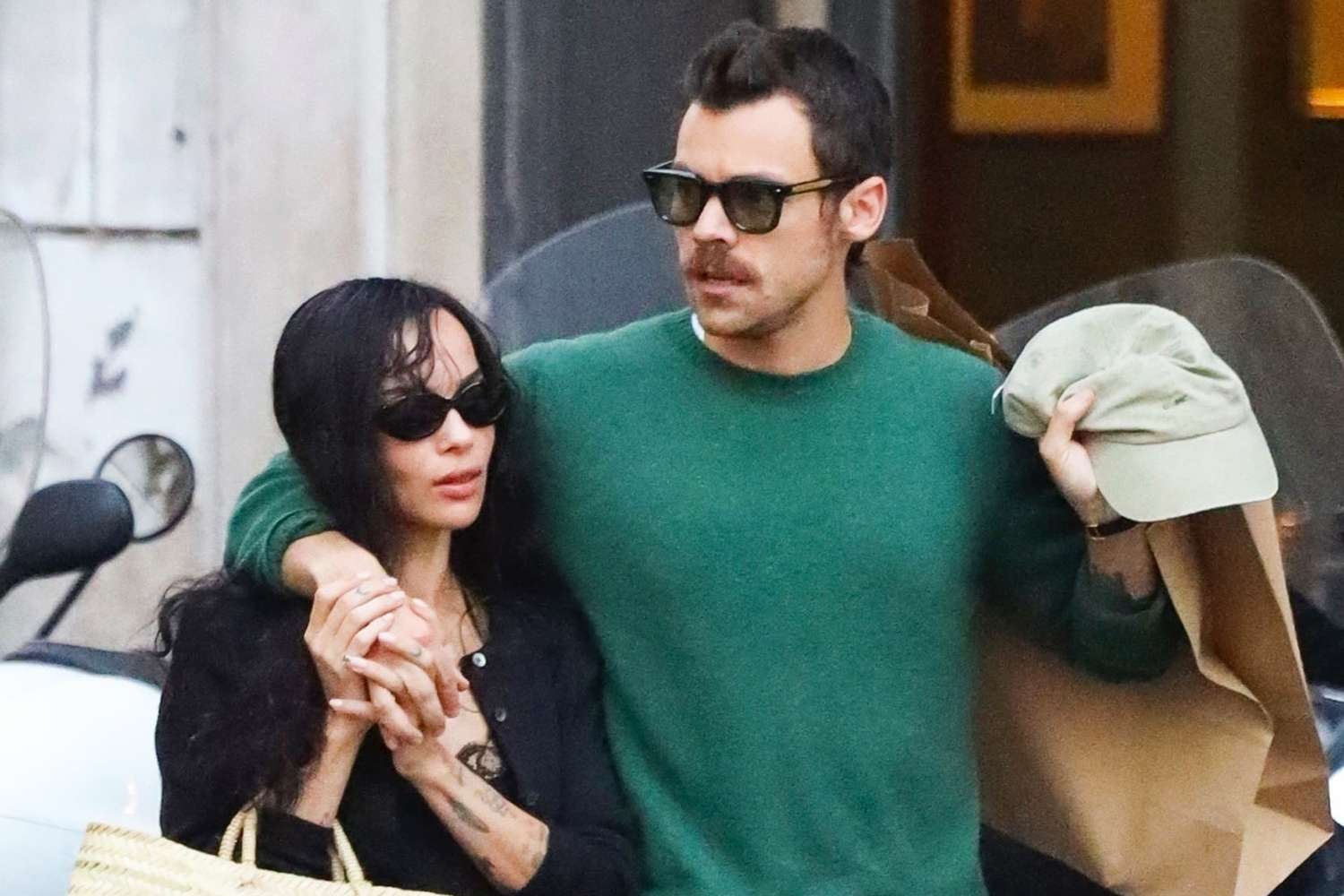 Zoë Kravitz and Harry Styles, both in sunglasses, walking closely together on a city street.