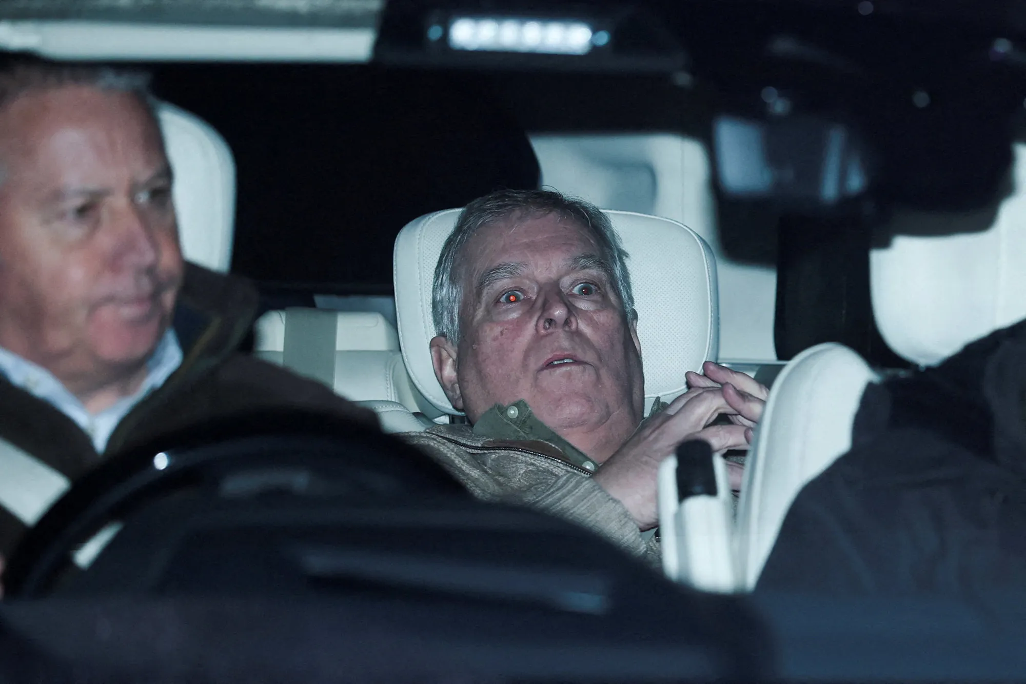 Andrew Mountbatten photographed through a car window, seated in the back of a vehicle with red-eye flash effect visible.
