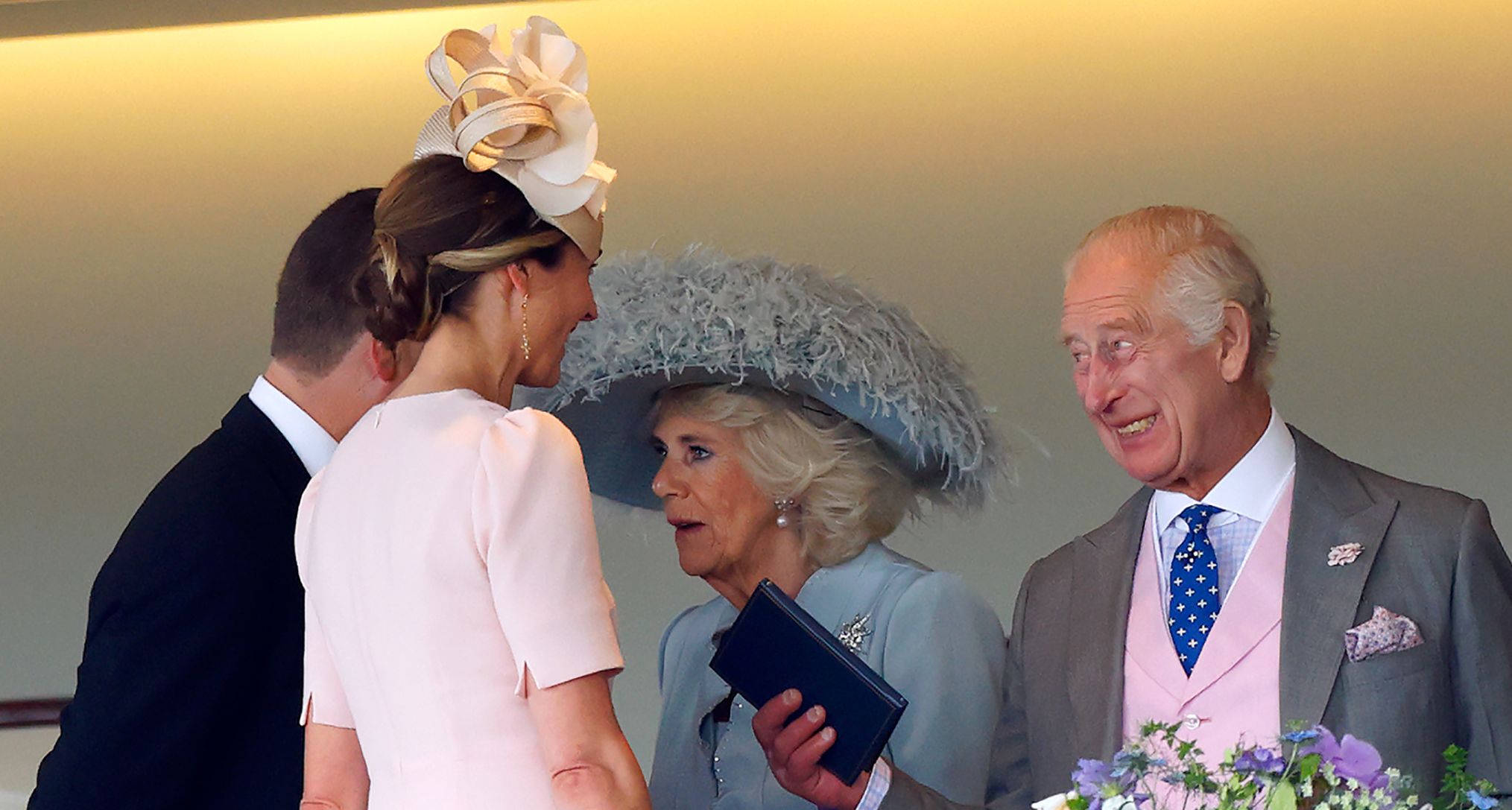 King Charles and Queen Camilla chatting with Peter Phillips and Harriet Sperling at a formal royal event, all dressed in elegant race day attire