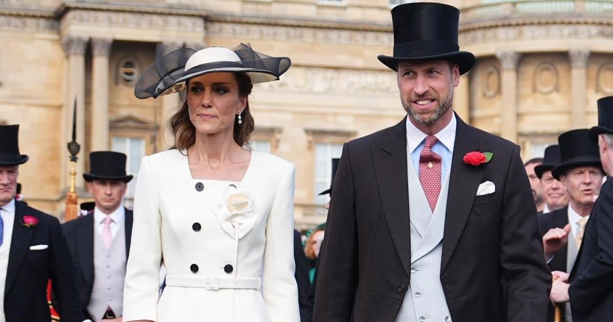 A man and woman in formal attire and top hats stand together at an elegant outdoor event near a grand classical building.