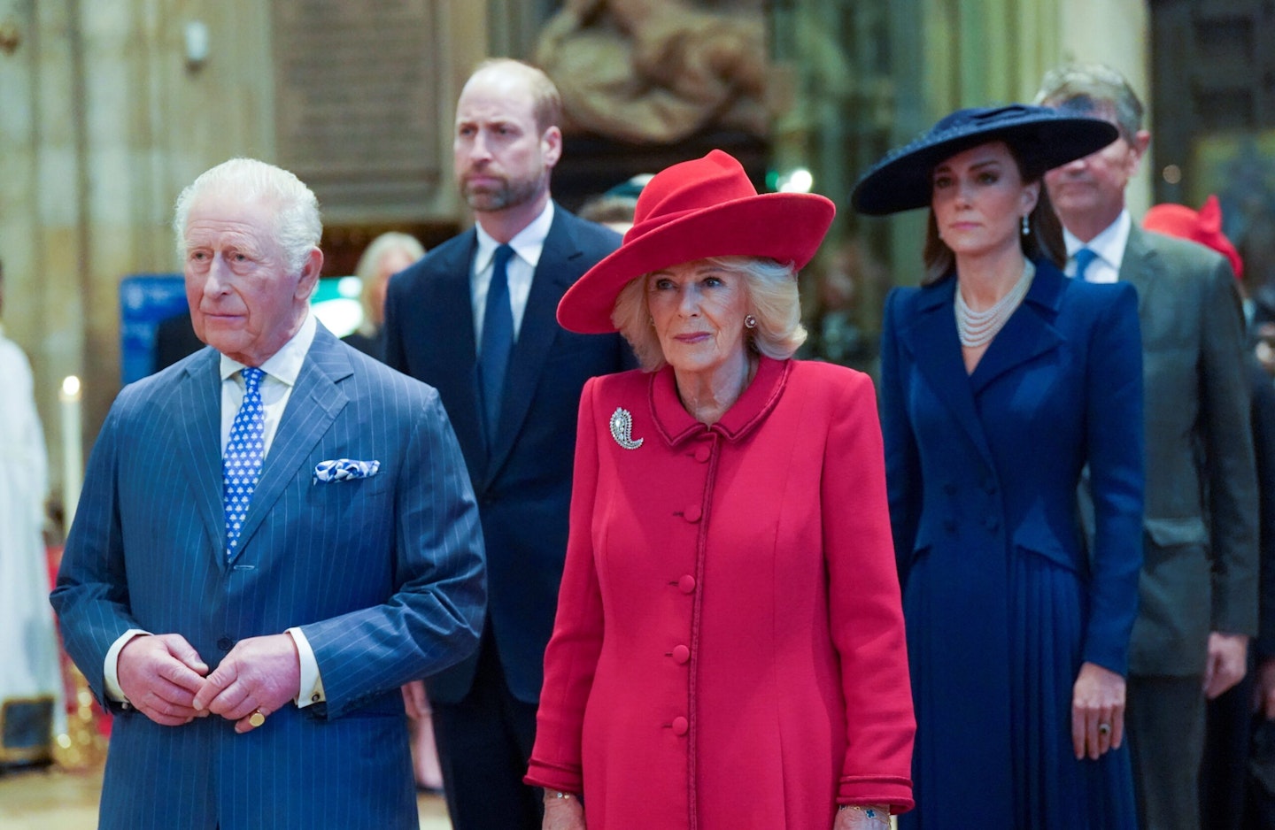 King Charles and Queen Camilla leading, with Prince William and Kate Middleton following behind, at a formal church ceremony.
