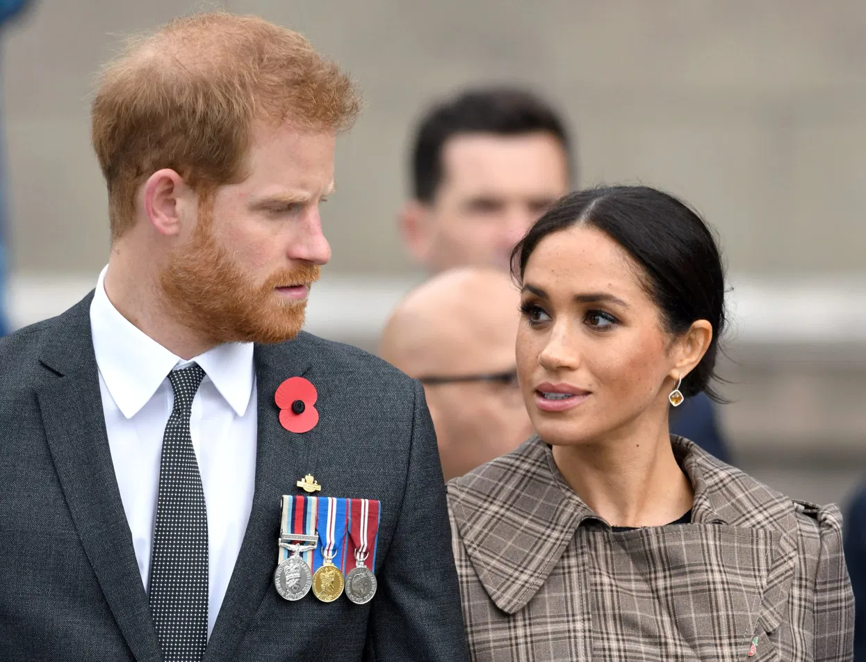 Prince Harry and Meghan Markle at a formal event, Harry wearing military medals and a poppy pin.