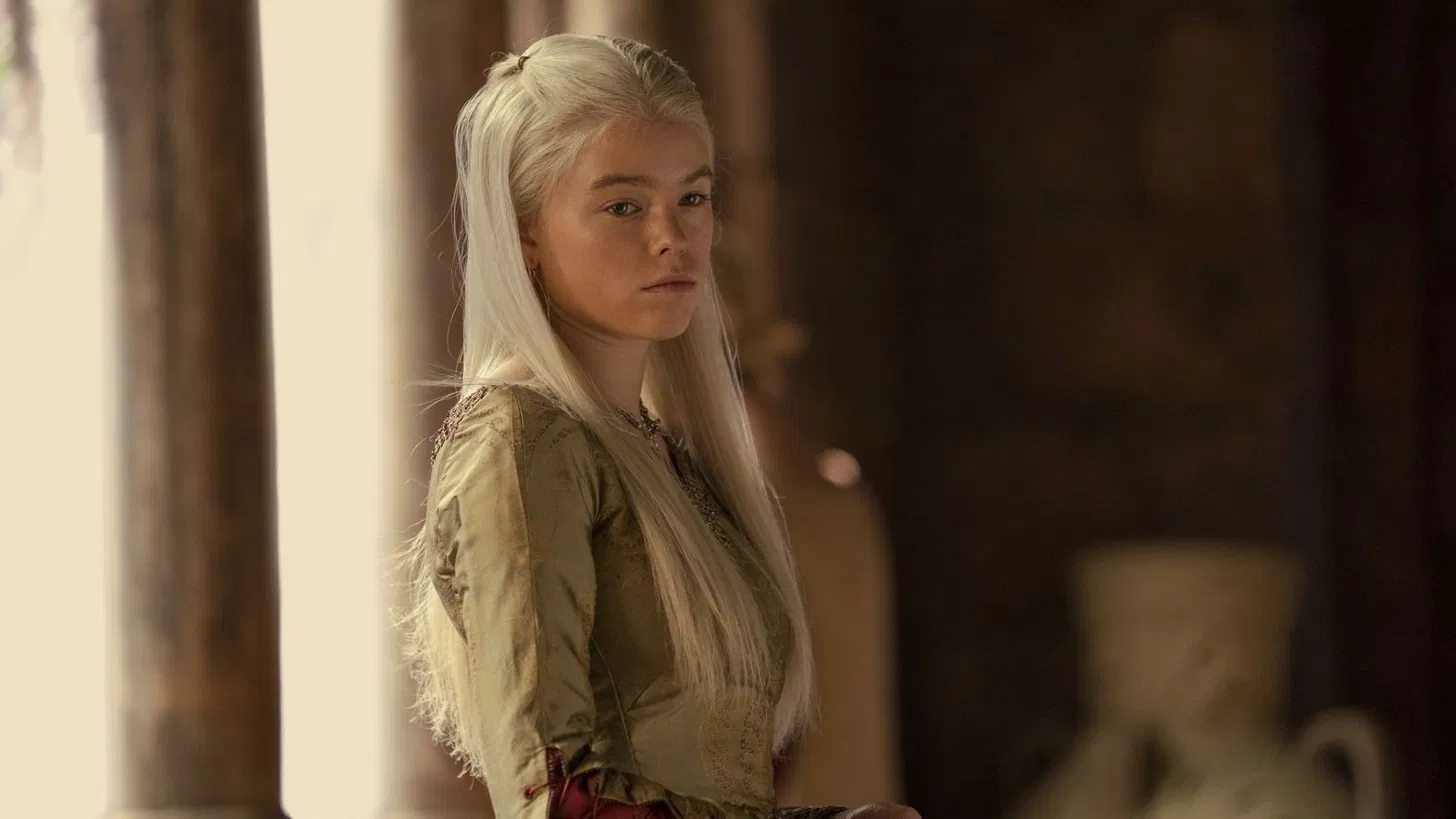 Milly Alcock as Rhaenyra Targaryen with long platinum hair in a medieval gown in a scene from House of the Dragon.