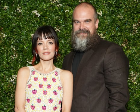 David Harbour and Lily Allen posing together at a formal event in front of a green hedge wall backdrop.