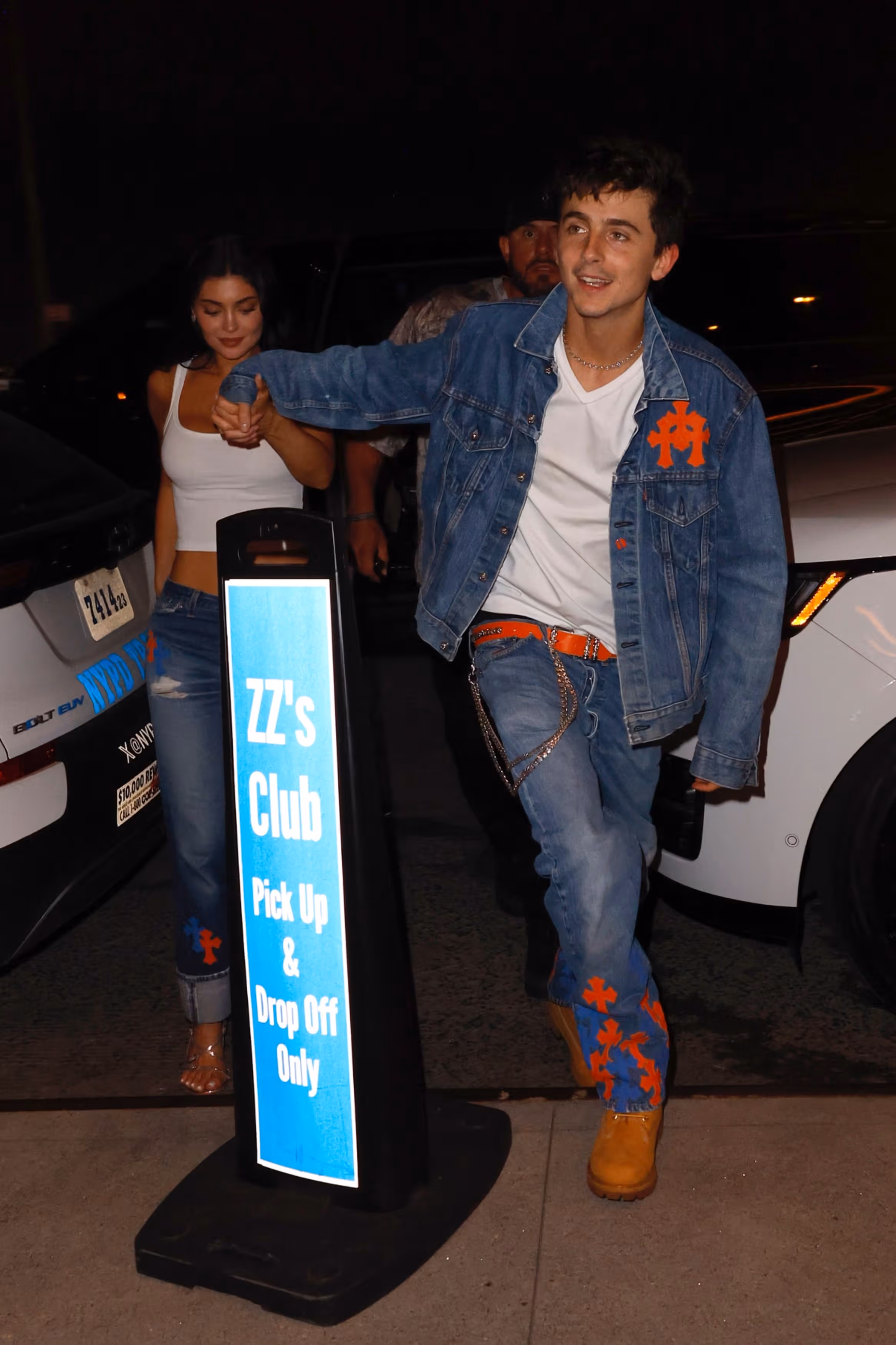 Timothée Chalamet and Kylie Jenner arriving hand in hand at ZZ's Club in Knicks-colored Chrome Hearts denim outfits.